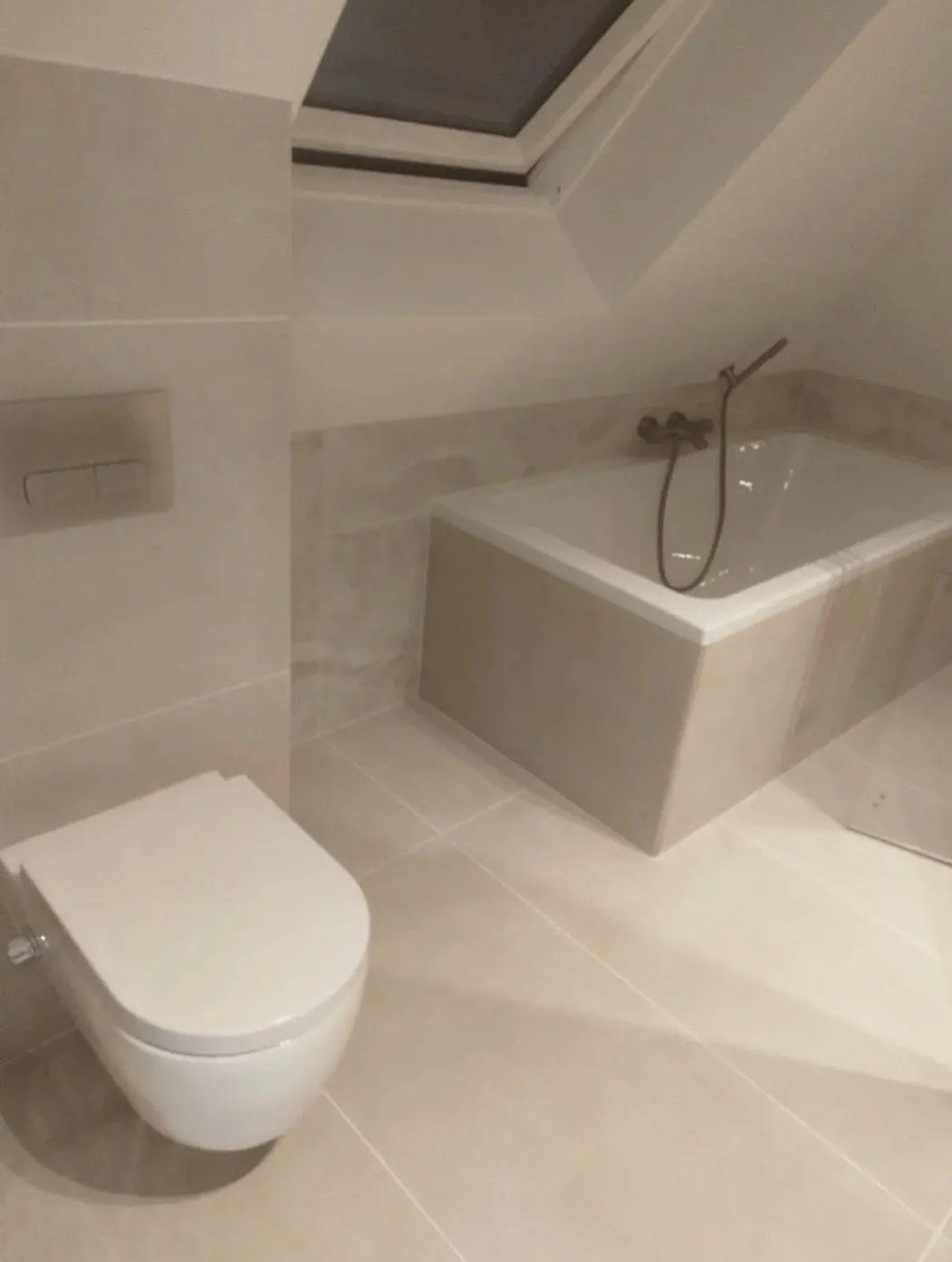 Bad en toilet in een lichte badkamer met zandkleurige tegels